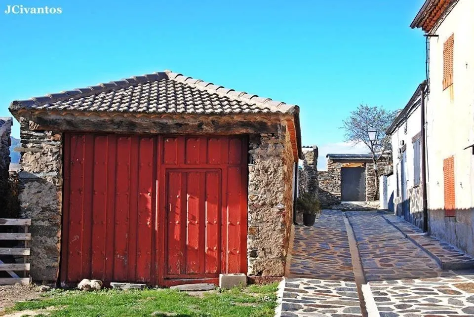 Calle empedrada de Becerril, con un portón rojo entre casas de pizarra