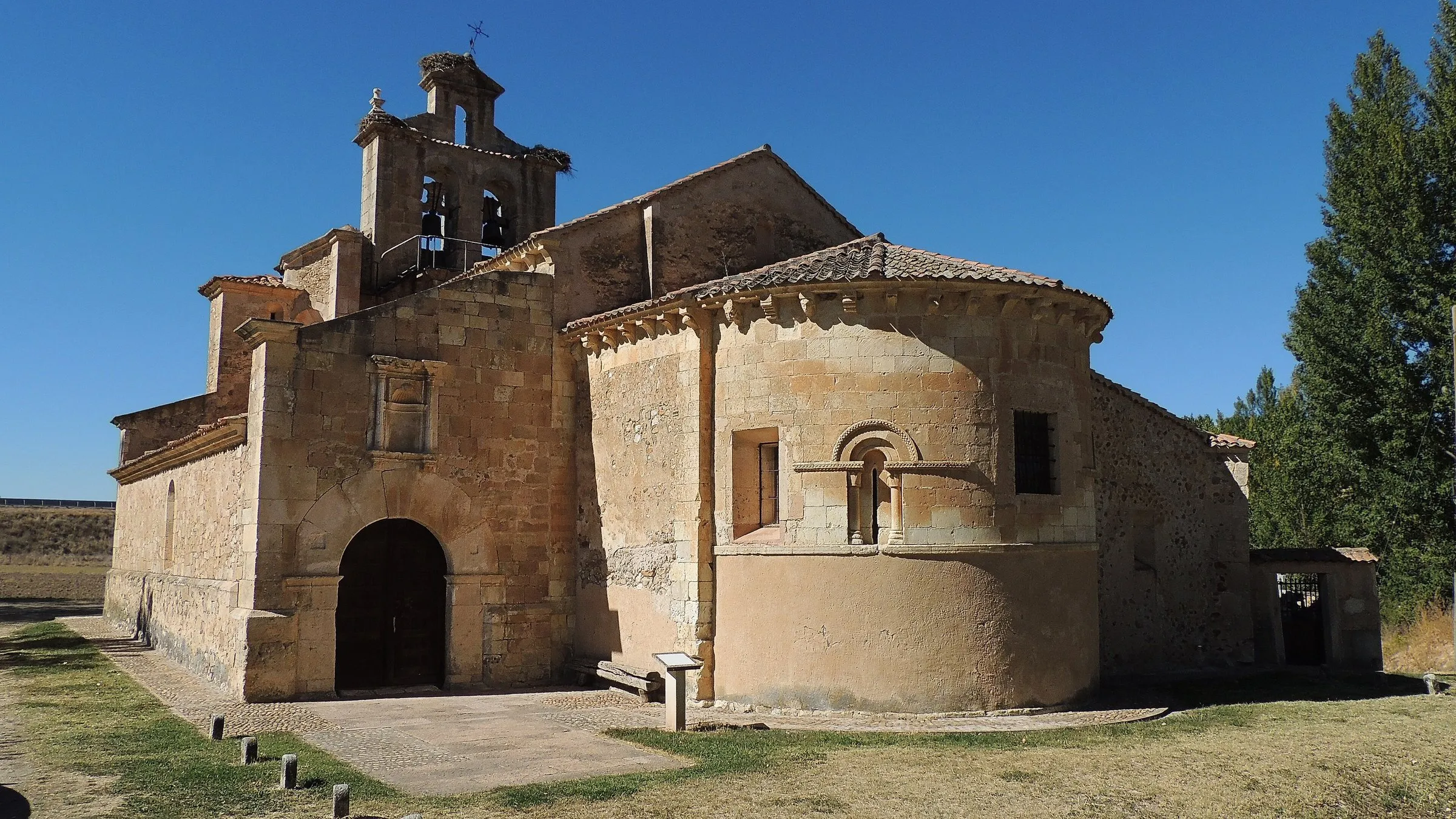 La iglesia de Nuestra Señora de la Asunción de Castillejo de Mesleón: el ábside románico con su ventana de arco, la espadaña con nidos de cigüeña y el pórtico cerrado