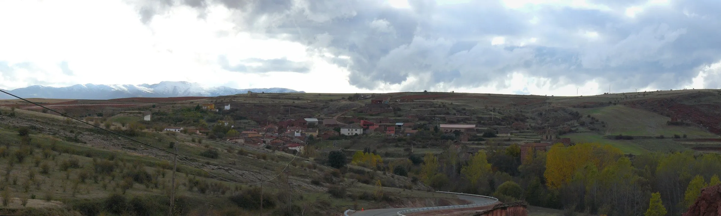 Cuevas de Ayllón entre tierras rojas, con la sierra nevada al fondo