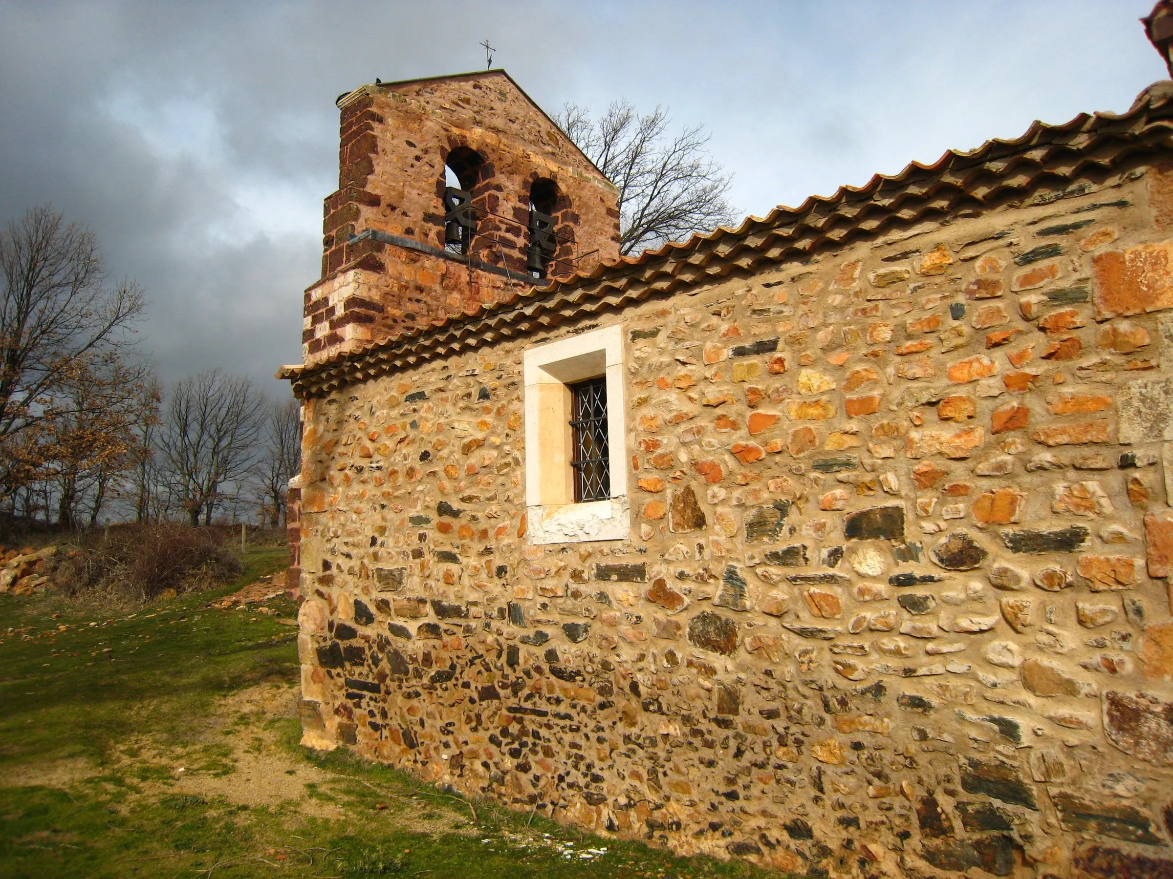 La espadaña de doble hueco de la iglesia de San Martín de Tours sobre el muro donde se mezclan la cuarcita, el rodeno y la pizarra