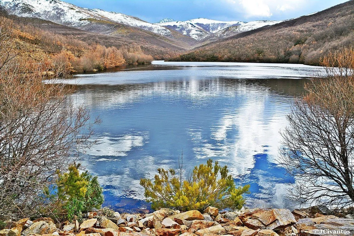 El embalse de Riofrío reflejando el cielo, con las cumbres nevadas de la Sierra de Ayllón al fondo