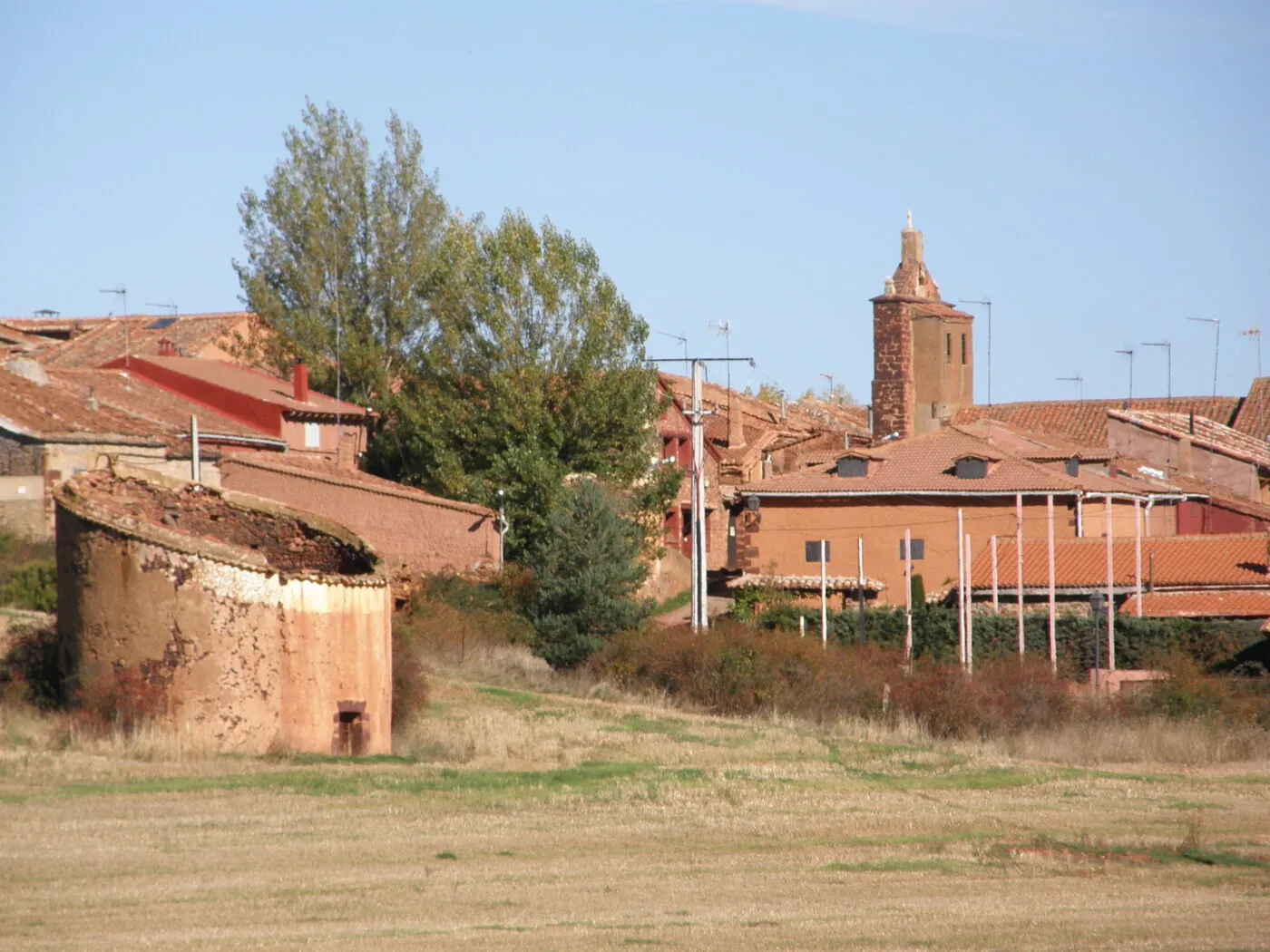El caserío rojo de Villacorta con la torre de Santa Catalina sobresaliendo, y un palomar redondo en ruina en primer plano, en otoño de 2008